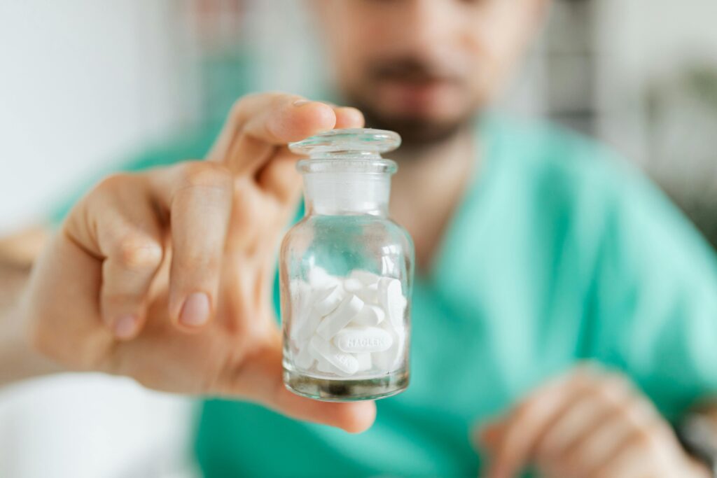 What Is a Compounding Pharmacy? Crop medical worker holding in hand glass transparent bottle while showing white tablets
