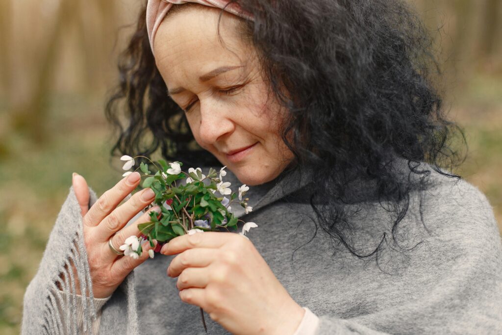 When Hormones Change, Life Changes Portrait of a woman enjoying the aroma of spring flowers outdoors.